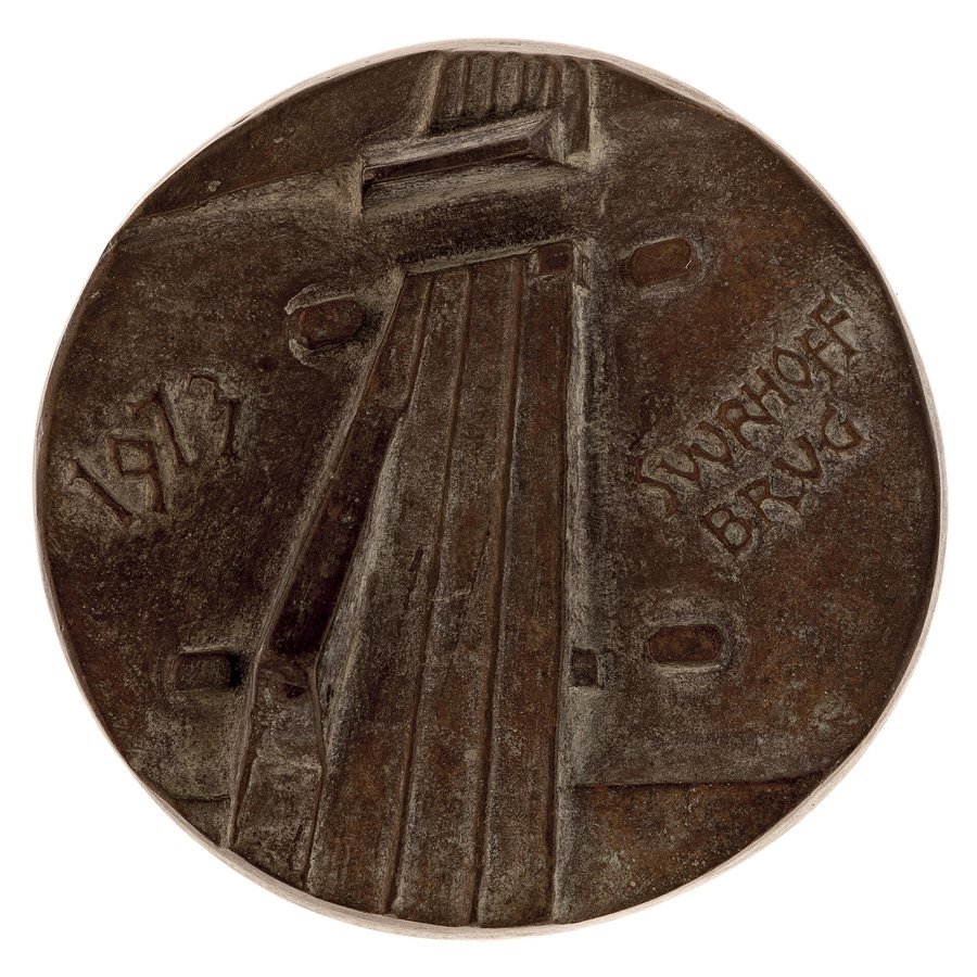 A round brown bronze medal with a relief of a bridge rising at an angle towards an opened bridge section, with the year 1973 on the left and the word Suurhoffbrug on the right.