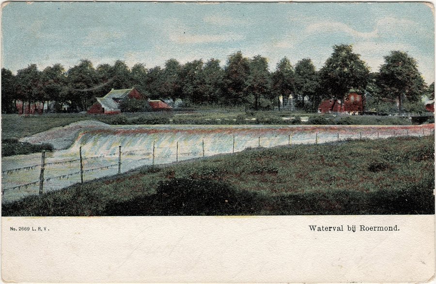 Old hand-coloured postcard of a wide, low waterfall over a weir, with a fence in the foreground, trees and red houses behind, and at the bottom the caption Waterval bij Roermond (Waterfall near Roermond).