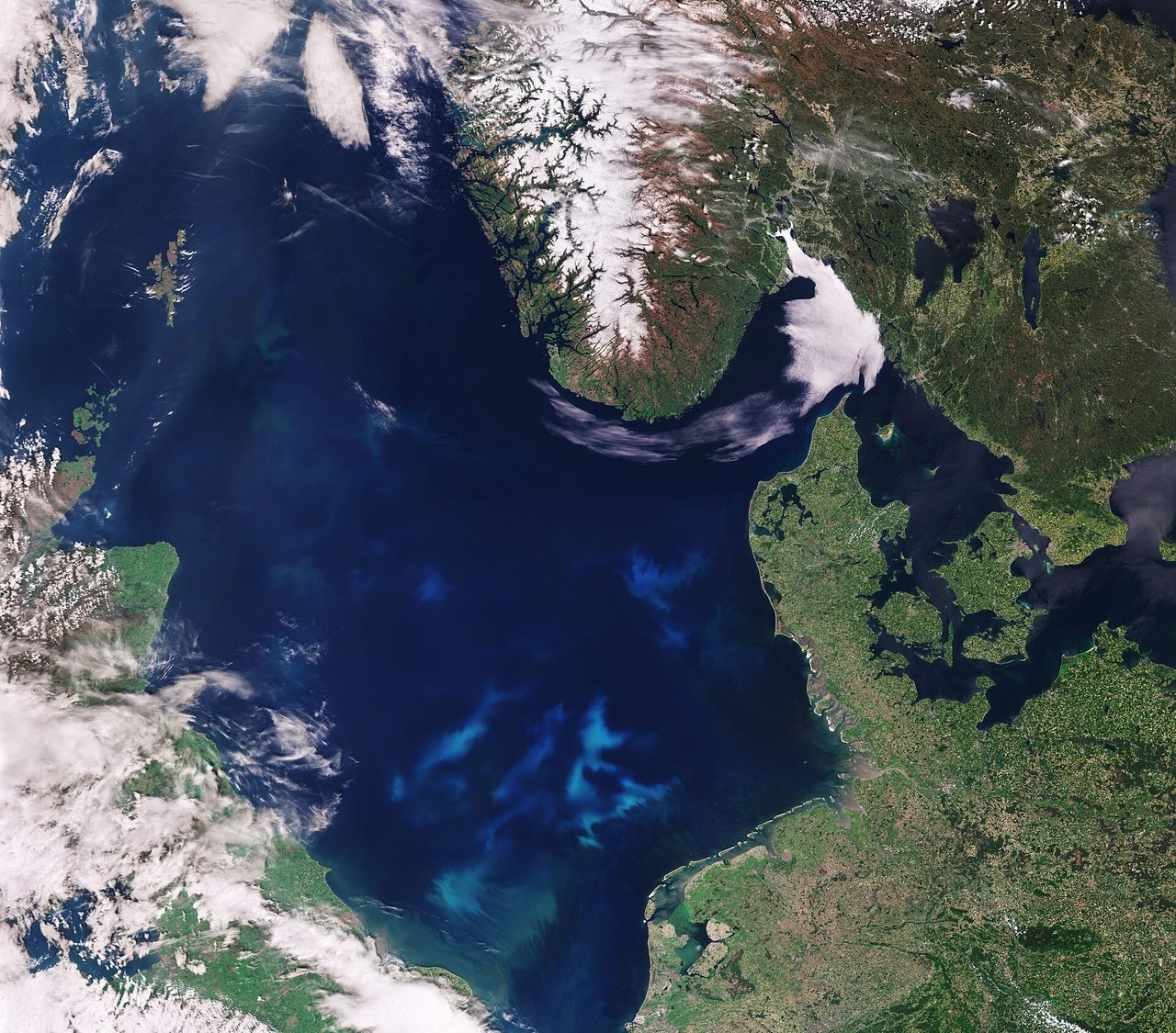 Satellitenbild eines dunkelblauen Meeres, umgeben von grünem Land und weißen Wolken, oben Norwegen, rechts Dänemark und unten die Niederlande, mit hellblauen Wirbeln im Wasser.