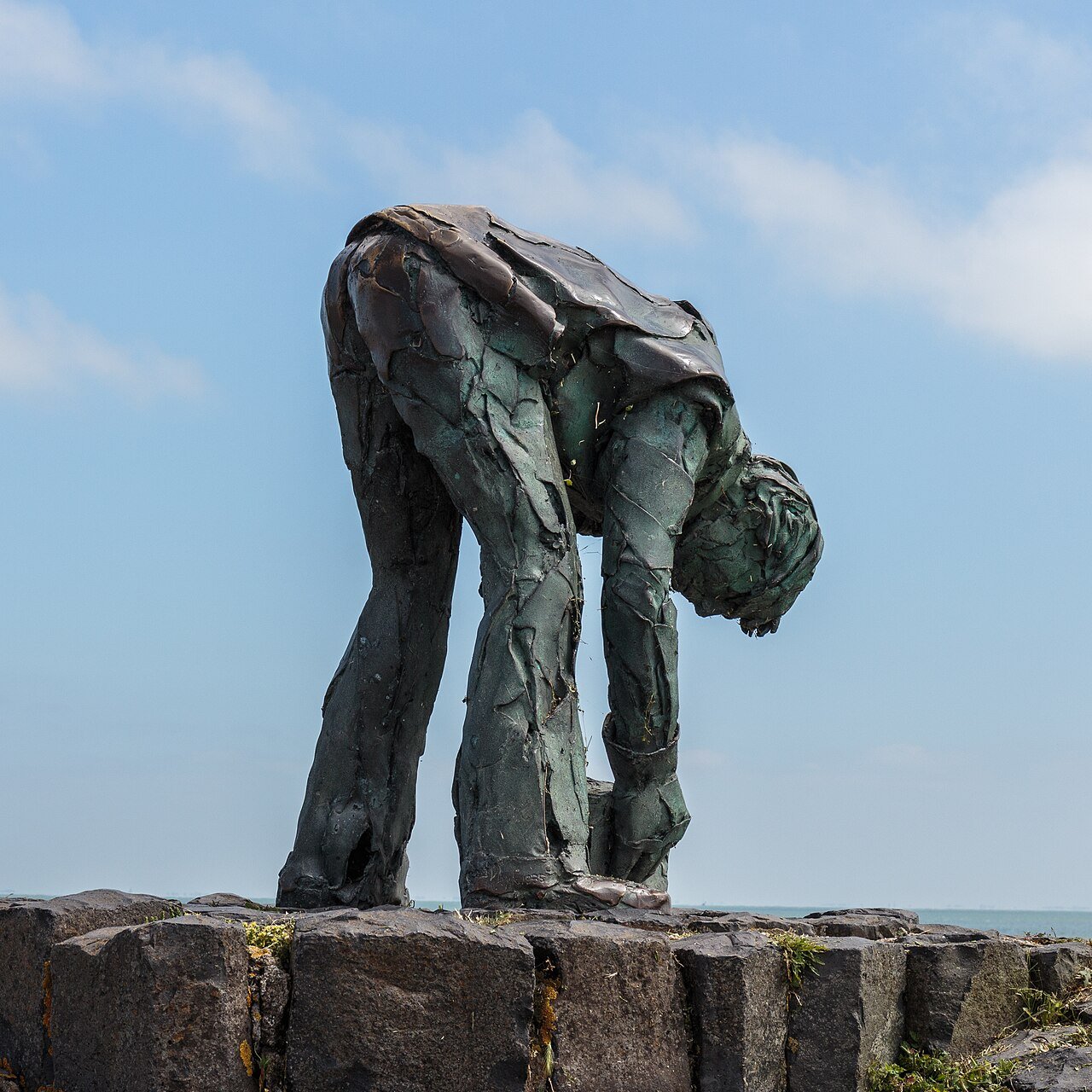 Bronzen beeld van een gebogen arbeider bij de Afsluitdijk