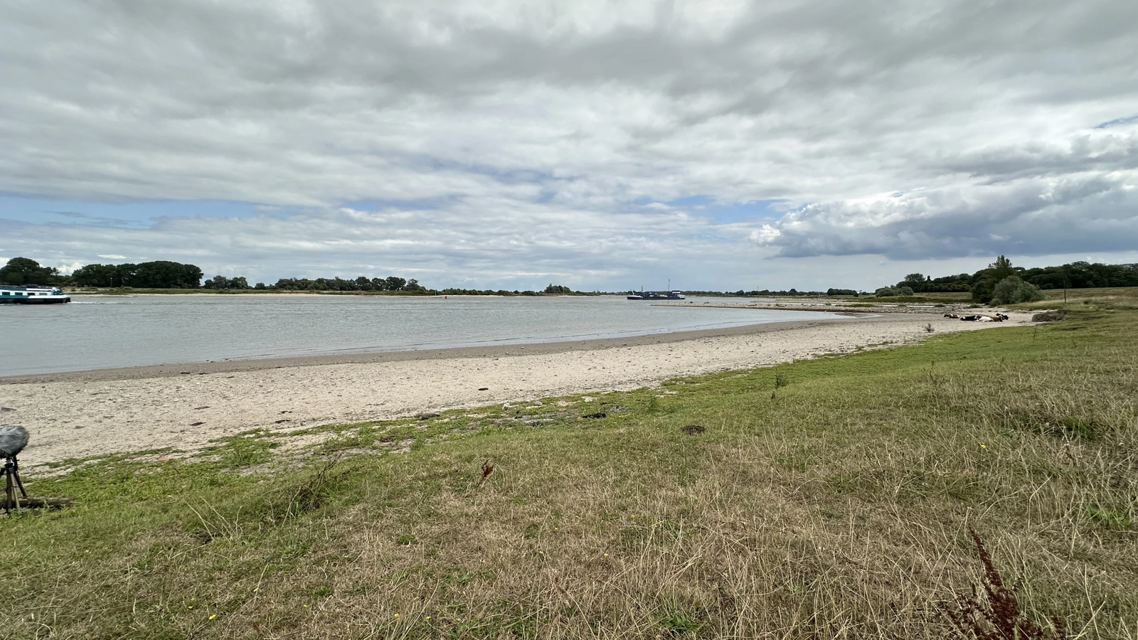 The Waal with a broad exposed bank beneath a cloudy sky.