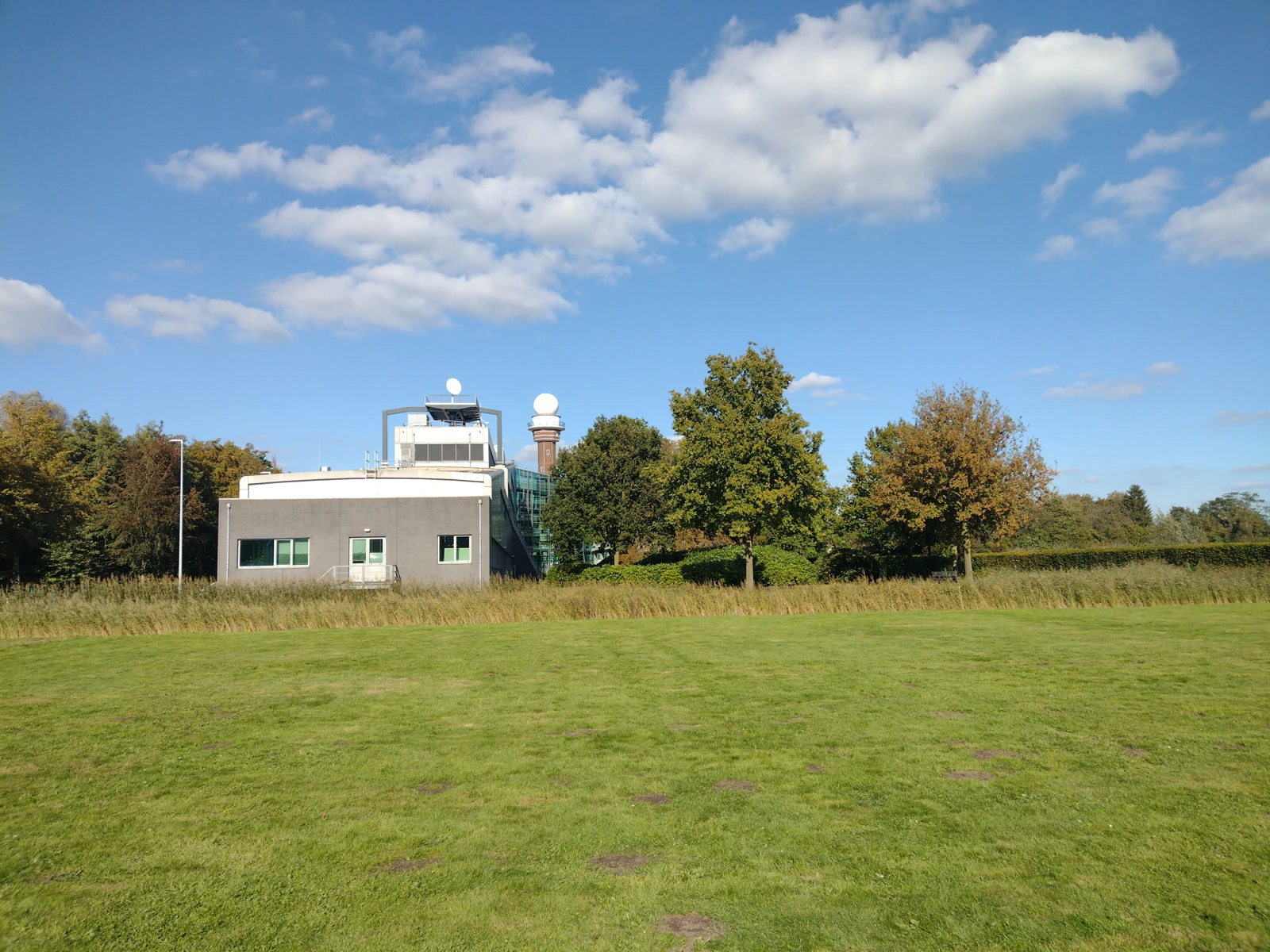A KNMI building behind a lawn and trees.