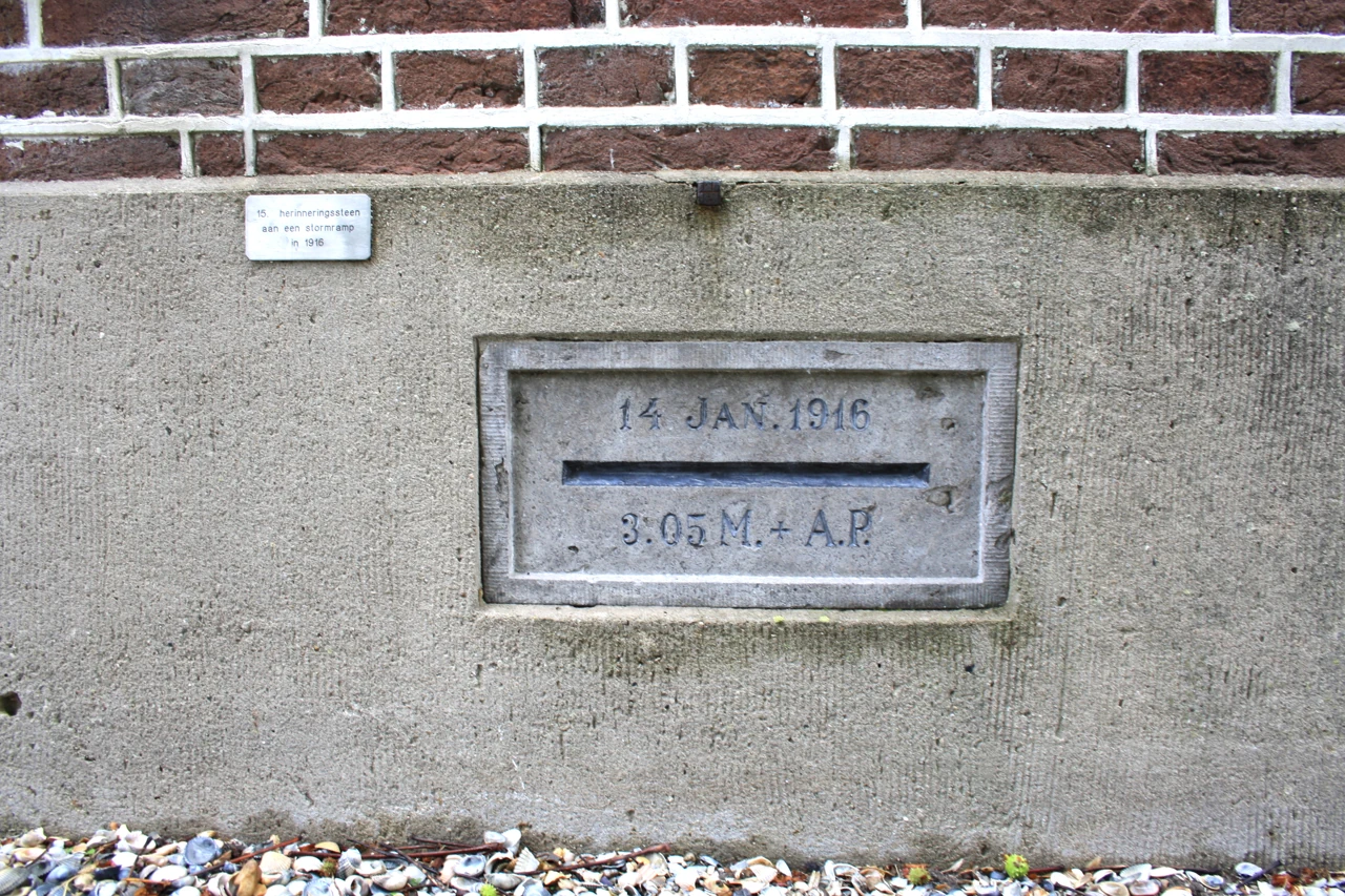 Een steen in een muur met de inscriptie 14 JAN. 1916 en een waterhoogte.